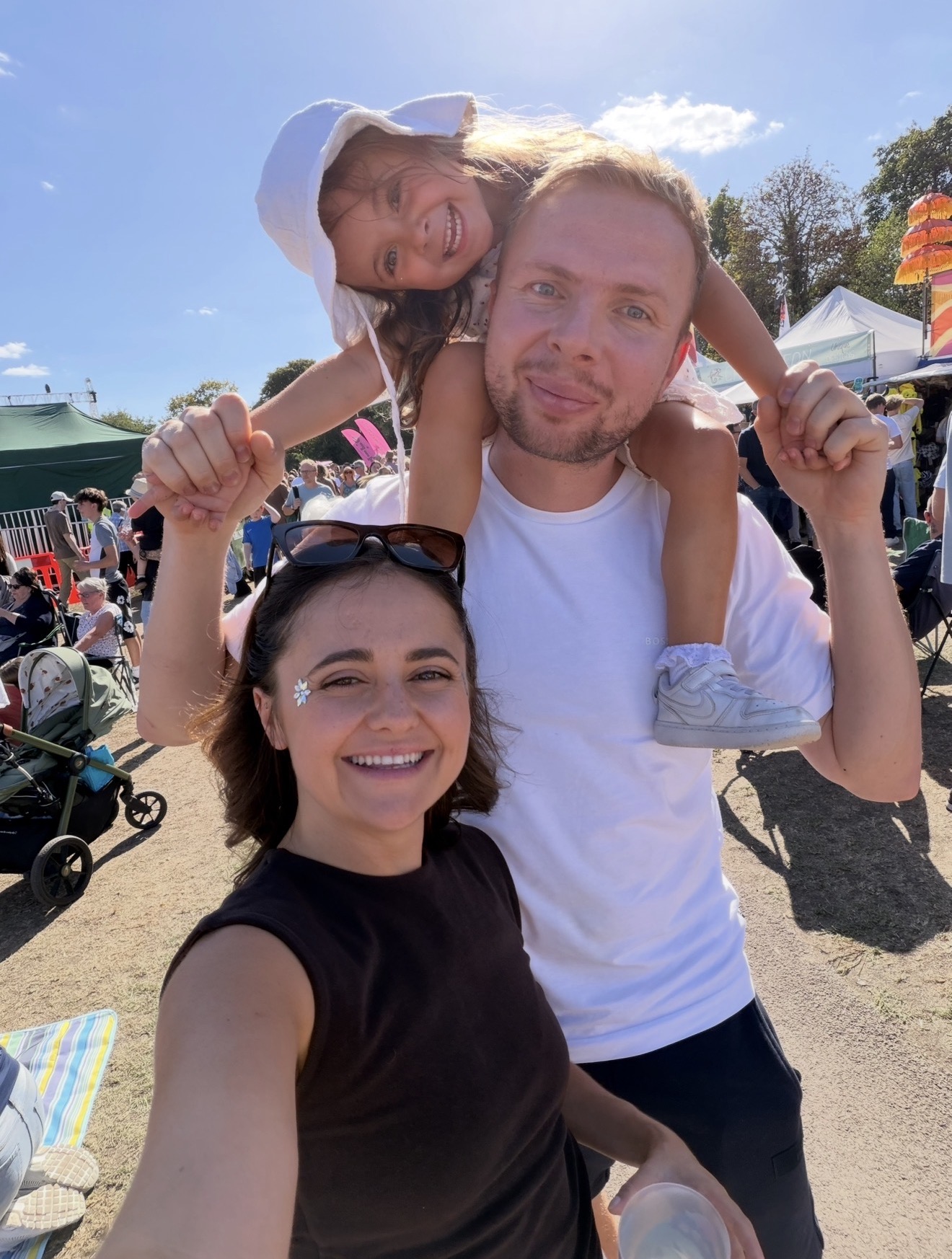 Layla at a festival with her daughter on her partner's shoulders